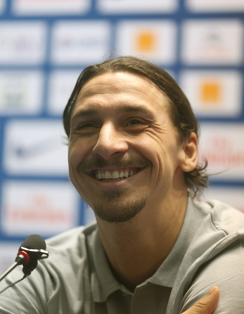 Zlatan ler stort. Han har håret i en hästsvans och har en grå tröja på sig.